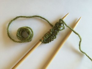 Two Rows of Knit Stitch on Wooden Needles.  Mistake near point because I stuck point through the middle of a strand.